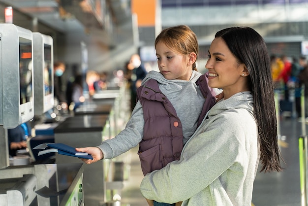 Impiegato irriconoscibile dell'aeroporto che controlla passaporti e dati biometrici mentre lavora con la famiglia dei passeggeri. Madre felice e sua figlia che hanno viaggio