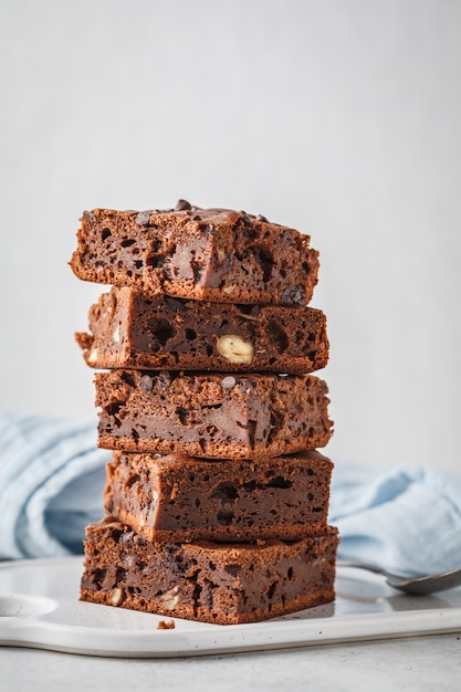 Impila pezzi di torta al cioccolato vegano con gocce di cioccolato e noci.