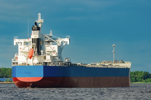 Importazione di merci. Grande nave da carico blu in movimento al porto di Riga