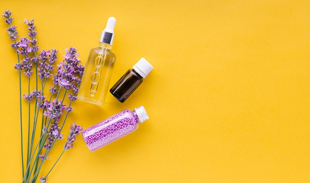 Impostare prodotti cosmetici per la cura della pelle alla lavanda prodotti di bellezza naturali termali erbe fresche di fiori di lavanda su sfondo giallo olio essenziale di lavanda siero crema perline da bagno piatto spazio copia laici