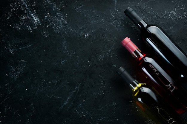 Impostare Una bottiglia di vino bianco rosso e rosato su uno sfondo di pietra nera Vista dall'alto Spazio libero per la copia