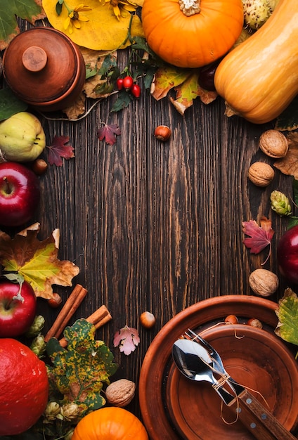 Impostazione del posto per la cena del Ringraziamento Zucche di frutta autunnale noci foglie cadute con piatto e posate Sfondo autunnale del ringraziamento