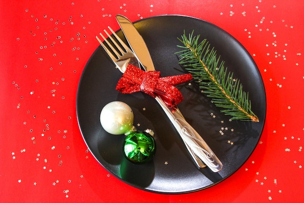 Impostazione della tavola di Natale in banda nera con palline colorate sul tavolo rosso spazio copia Cena di Natale