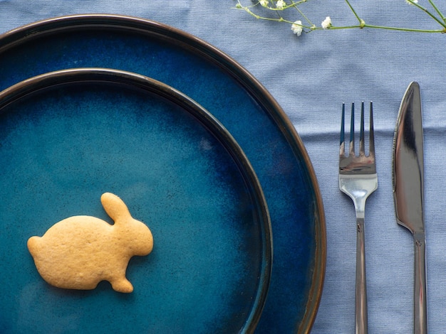 Impostazione festiva della tavola di Pasqua con biscotti e fiori su sfondo blu