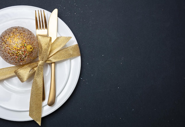 Impostazione tabella Natale Capodanno Posate d'oro su bianco set di piatti sfondo nero