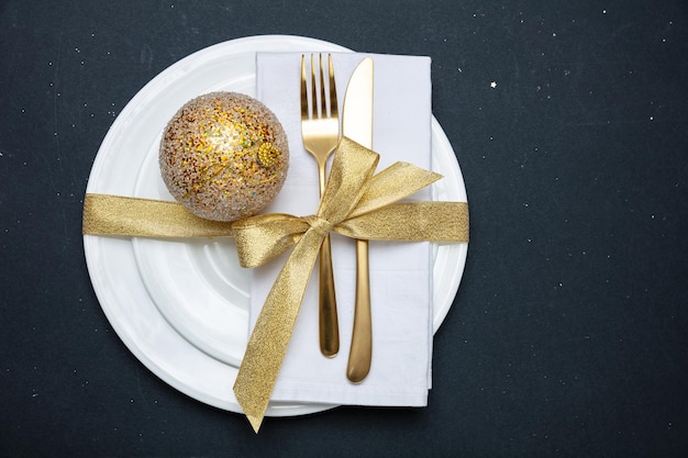 Impostazione tabella Natale Capodanno Posate d'oro su bianco set di piatti sfondo nero