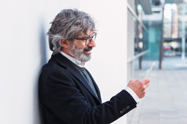 Imprenditore anziano che utilizza il telefono cellulare per digitare un messaggio ai partner dopo la conferenza