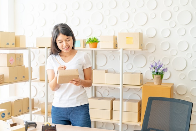 Imprenditore asiatico che lavora a casa con il contenitore di imballaggio sul posto di lavoro