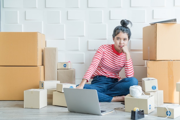 Imprenditore asiatico delle donne che lavora a casa con il contenitore di imballaggio sul posto di lavoro