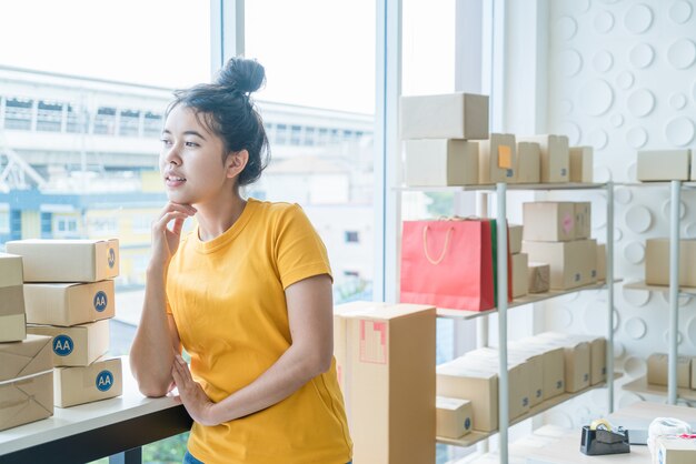 Imprenditore asiatico delle donne che lavora a casa con il contenitore di imballaggio sul posto di lavoro