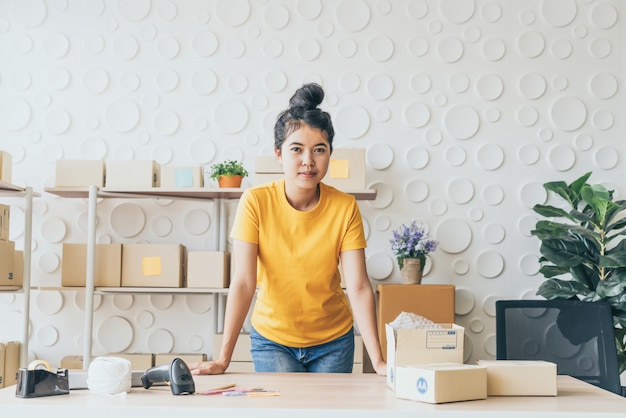 Imprenditore asiatico delle donne che lavora a casa con il contenitore di imballaggio sul posto di lavoro