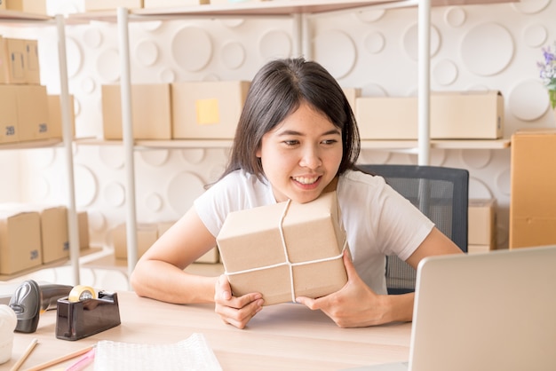 Imprenditore asiatico delle donne che lavora a casa con il contenitore di imballaggio sul posto di lavoro