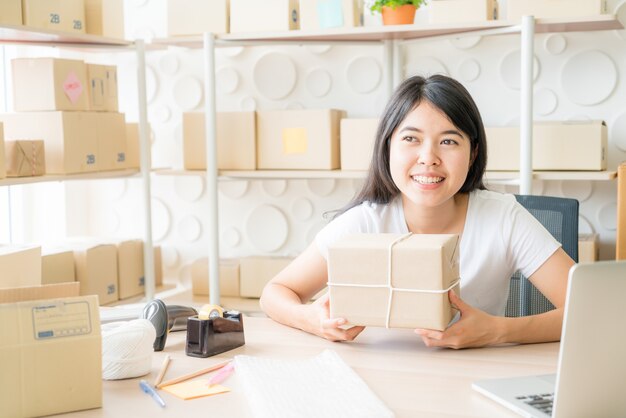 Imprenditore asiatico delle donne che lavora a casa con il contenitore di imballaggio sul posto di lavoro