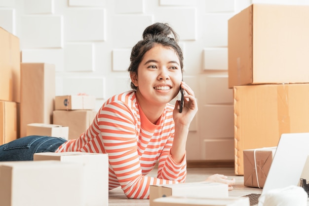 Imprenditore asiatico delle donne che lavora a casa con il contenitore di imballaggio sul posto di lavoro
