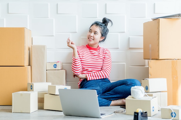 Imprenditore asiatico delle donne che lavora a casa con il contenitore di imballaggio sul posto di lavoro