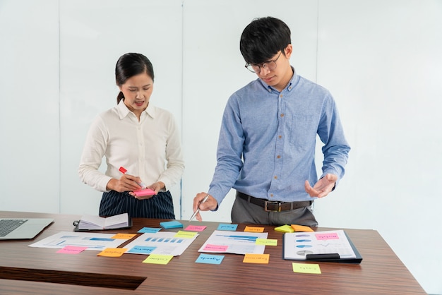 Imprenditore attaccare note colorate al brainstorming sul tavolo lavorando su un nuovo progetto per condividere l'idea di pensare a come pianificare un nuovo caso.