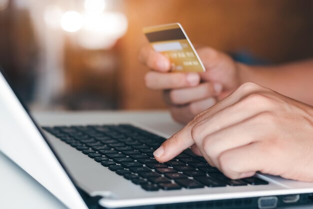 Imprenditore che tiene in mano una carta di credito con l'uso di un portatile per lo shopping online mentre fa gli ordini a casa business lifestyle technology ecommerce digital banking e concetto di pagamento online