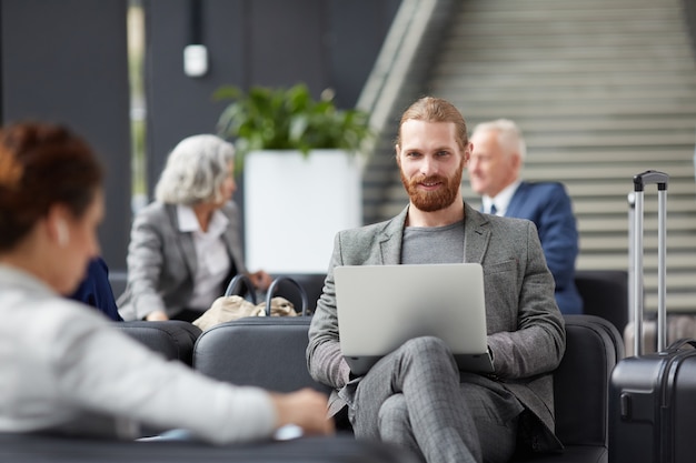 Imprenditore dalla barba rossa che utilizza computer portatile nell'aeroporto