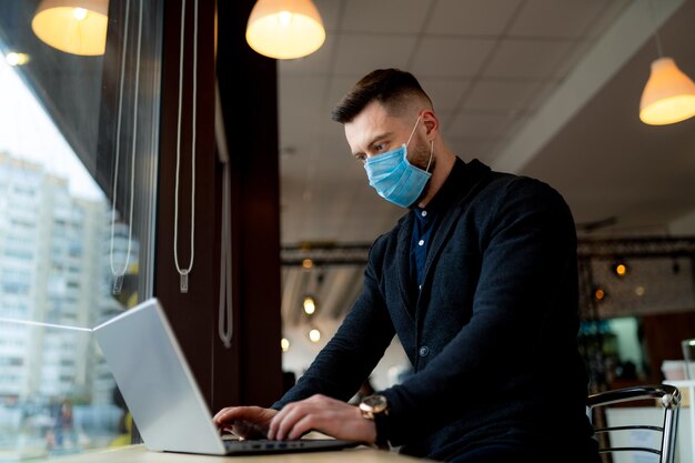 Imprenditore di successo che lavora in maschera medica. Mettere in quarantena il lavoro al chiuso. Ritratto maschile in maschera.