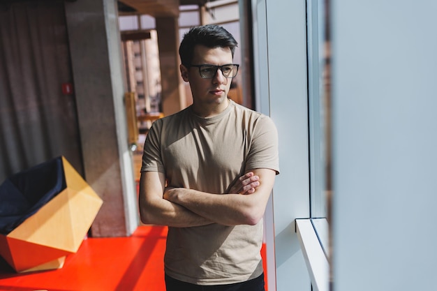 Imprenditore di successo in ufficio in piedi vicino alla finestra durante una giornata di lavoro in azienda un capo aziendale di successo si sente bene da uno stile di vita ricco