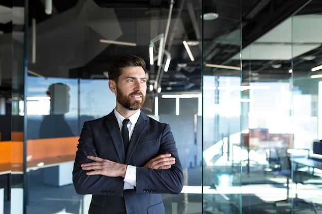 Imprenditore di successo in un moderno ufficio uomo con le mani piegate sulla croce distoglie lo sguardo e sorride