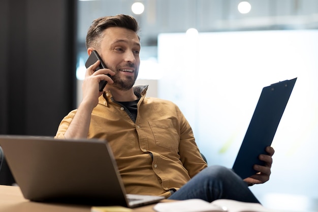 Imprenditore di successo parlando al cellulare guardando i documenti in ufficio