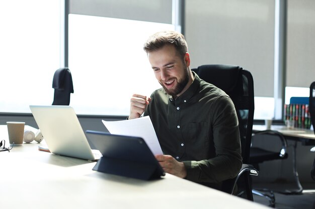 Imprenditore di successo sta studiando documenti con sguardo attento e concentrato.