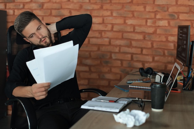 Imprenditore di successo sta studiando documenti con sguardo attento e concentrato.