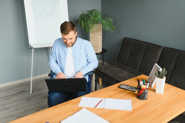 Imprenditore disabile seduto in sedia a rotelle utilizzando il computer sul posto di lavoro