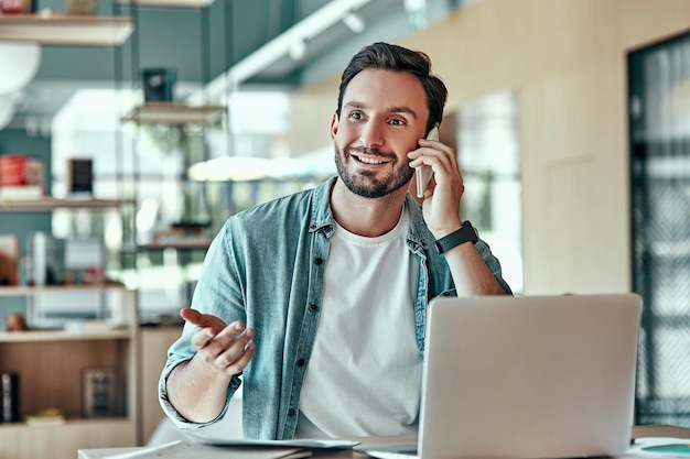 Imprenditore emotivo con conversione su smartphone Uomo che lavora su un computer portatile nella caffetteria