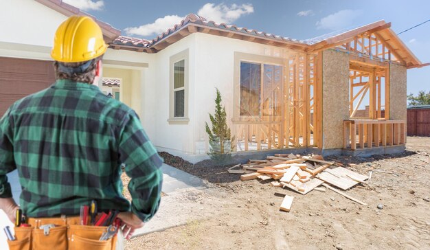 Imprenditore in piedi fuori dalla costruzione del telaio e foto della nuova casa