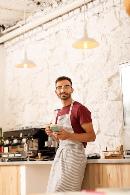 Imprenditore in piedi nella sua caffetteria con interni moderni