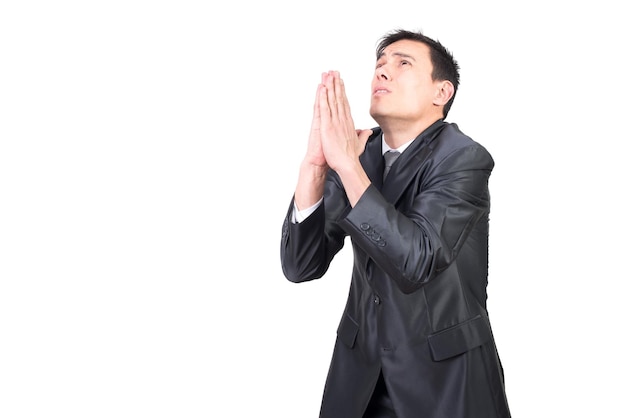 Imprenditore maschio bello in abito di classe che prega e alza lo sguardo mentre si trova su uno sfondo bianco