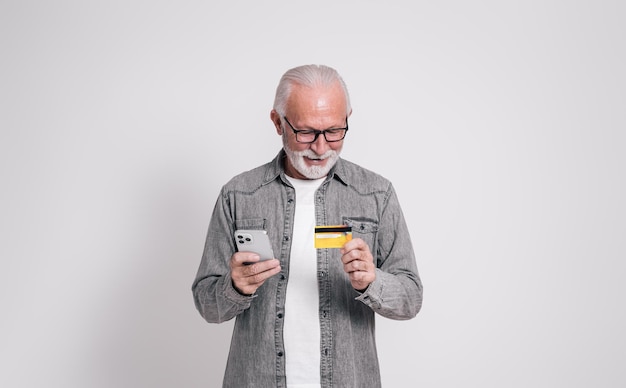 Imprenditore maschio che utilizza una carta di credito e un telefono cellulare per il pagamento online su sfondo bianco