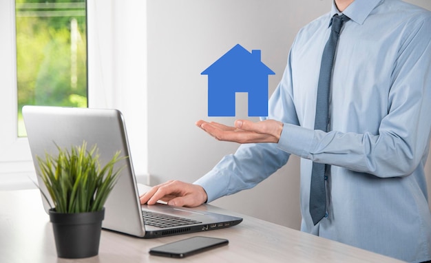 Imprenditore maschio mano azienda icona della casa su sfondo blu Assicurazione proprietà e sicurezza conceptReal estate conceptBanner con spazio di copia