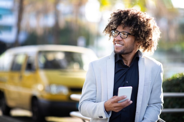 Imprenditore maschio nero di mezza età positivo che utilizza il cellulare per controllare le e-mail durante una pausa e