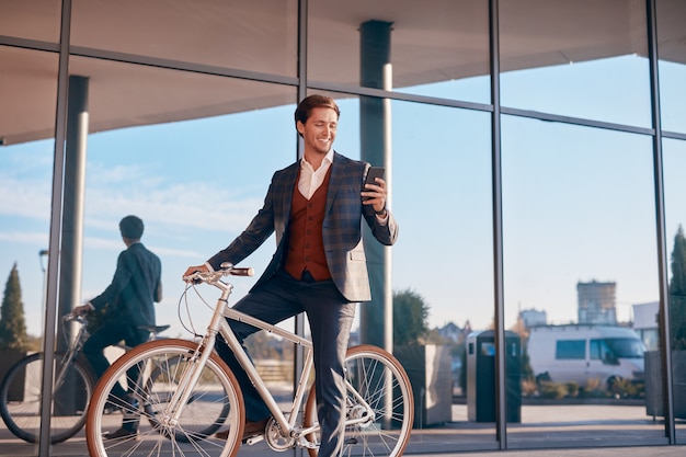 Imprenditore maschio utilizza lo smartphone in bicicletta