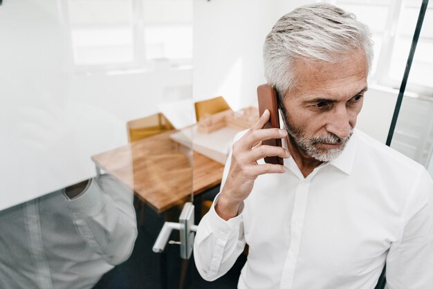 Imprenditore maturo al telefono in ufficio