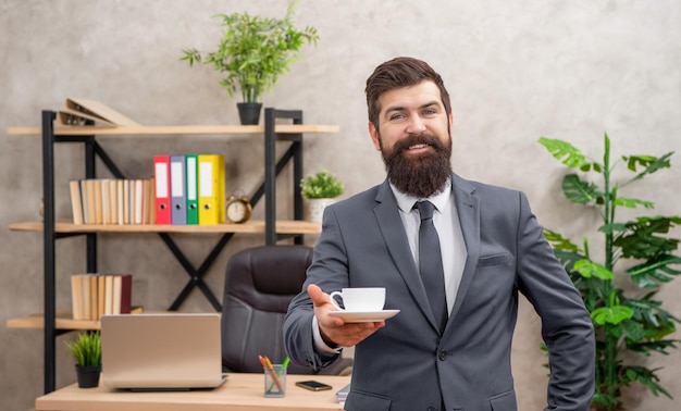 imprenditore maturo e felice in giacca che fa una pausa caffè alla pausa pranzo in ufficio