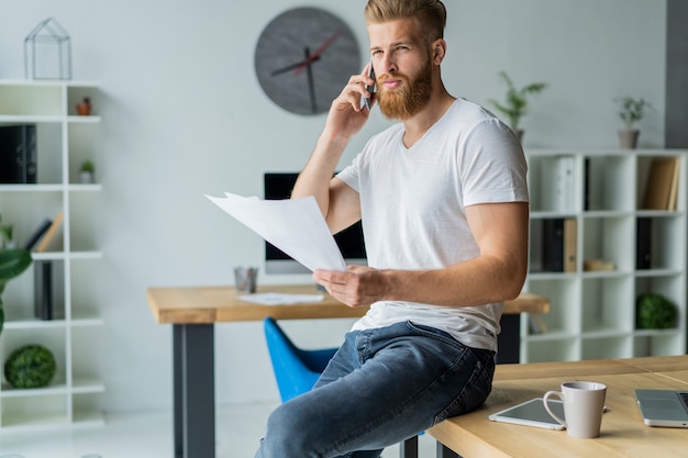 Imprenditore parlando al cellulare mentre è seduto in ufficio.