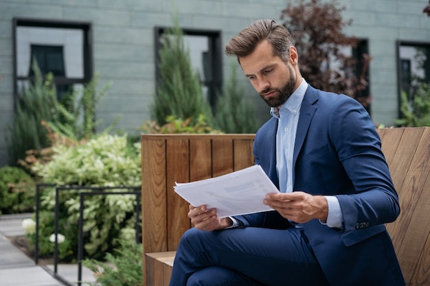 Imprenditore pensieroso che legge un contratto commerciale o un rapporto finanziario che analizza documenti