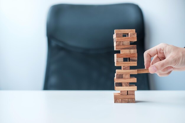 Imprenditore posizionando o tirando il blocco di legno sulla torre Pianificazione aziendale Gestione del rischio Soluzione e strategia Concetti