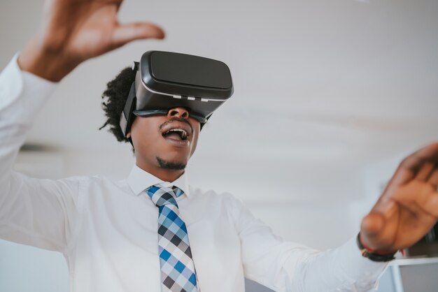 Imprenditore professionista utilizzando l'auricolare per realtà virtuale in una pausa dal lavoro presso un ufficio moderno. Concetto di business e tecnologia.