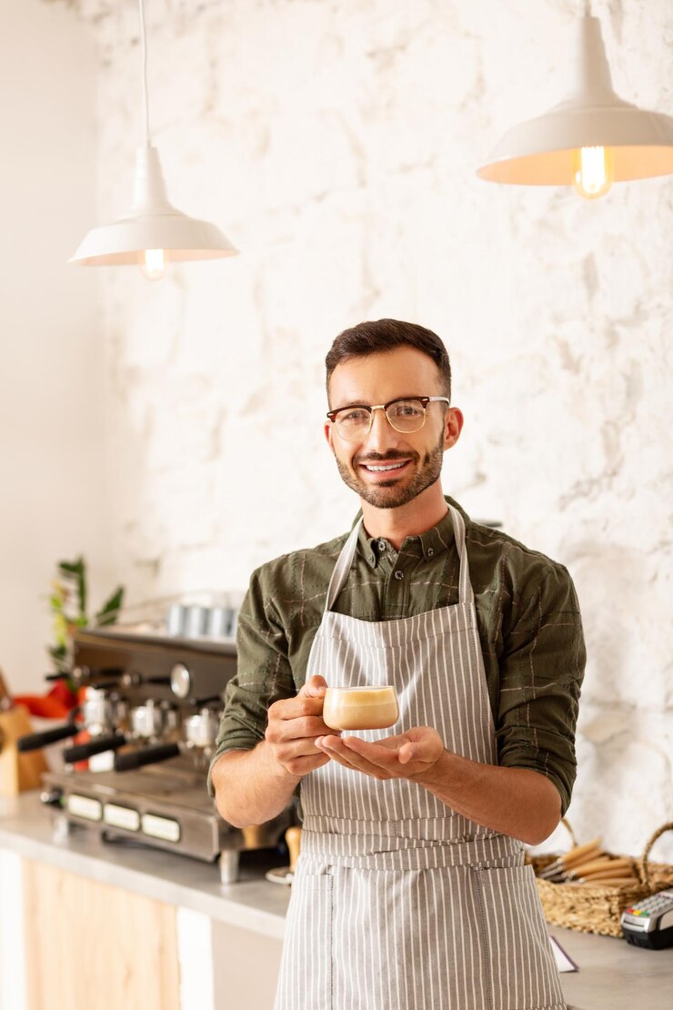 Foto imprenditore proprietario di una caffetteria che tiene una tazza di cappuccino