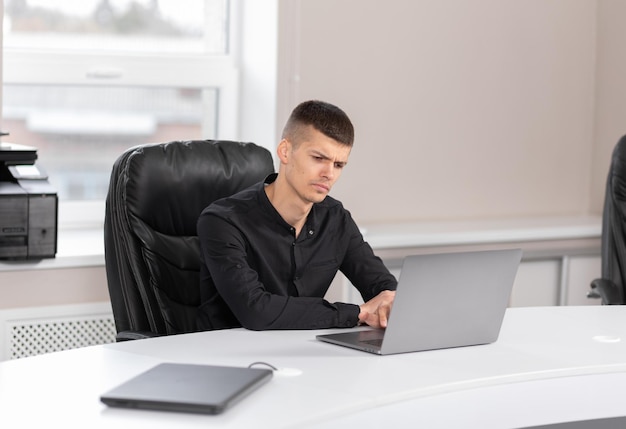 Imprenditore seduto al lavoro guardando laptop Concetto di lavoro d'ufficio