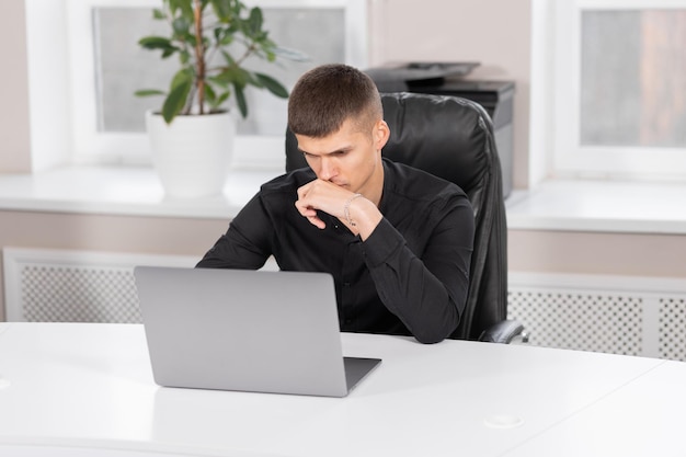 Imprenditore seduto al lavoro guardando laptop Concetto di lavoro d'ufficio