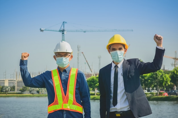 Imprenditore Senior Engineer che indossa la maschera facciale mostra il successo in cantiere