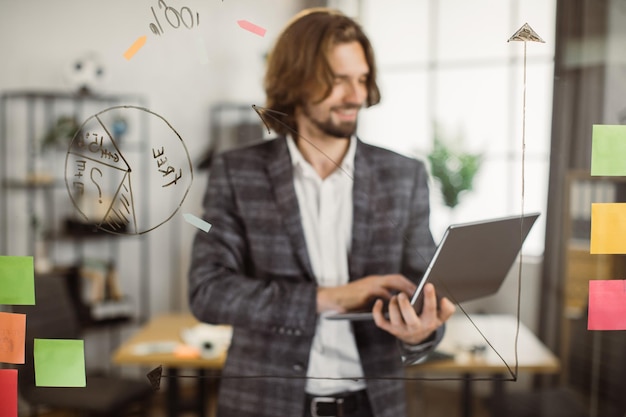 Imprenditore sorridente che digita sulla tastiera del computer portatile in ufficio