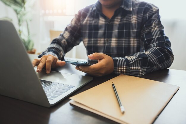 Imprenditore tenendo il telefono e utilizzando laptop al lavoro