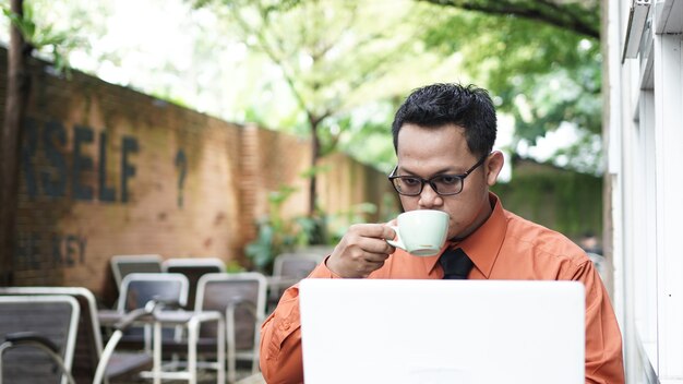 Imprenditori che lavorano al computer che bevono caffè e sorridono